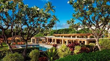 A resort with a swimming pool, palm trees, and a modern building.