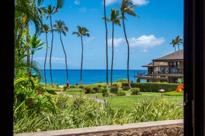 A view of a tropical resort with palm trees, a clear blue sky, and a body of water in the background. - Wailea Elua, #1601 1 Bedroom Condo by RedAwning (Kihei)