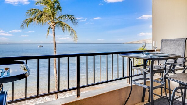 A balcony with a view of the sea, a palm tree, and a table with chairs. - Sugar Beach Resort, #ph27 1 Bedroom Condo by RedAwning (Kihei)