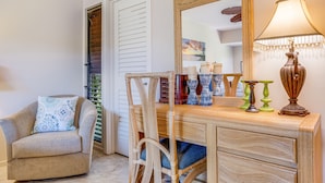 A room with a wooden vanity, a chair with patterned cushions, a mirror, and a lamp. - Wailea Elua, #2201^ 2 Bedroom Condo by RedAwning (Kihei)