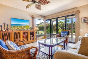 A spacious living room with a large television, comfortable seating, and a view of the outdoors.