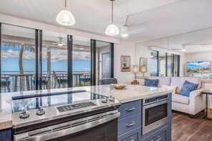 A modern kitchen with a large island, built-in oven, and a view of the ocean.