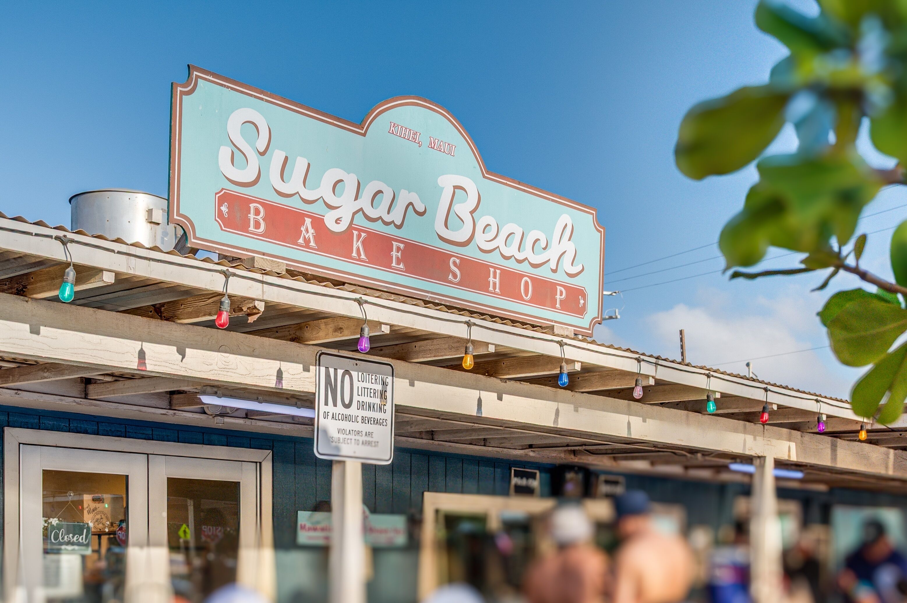 A storefront with a sign reading 'Sugar Beach Bake Shop' and a 'No Loitering, Littering, Drinking of Alcoholic Beverages' sign below.