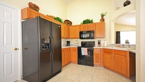 A kitchen with wooden cabinets, a stainless steel refrigerator, a microwave, and a stove.
