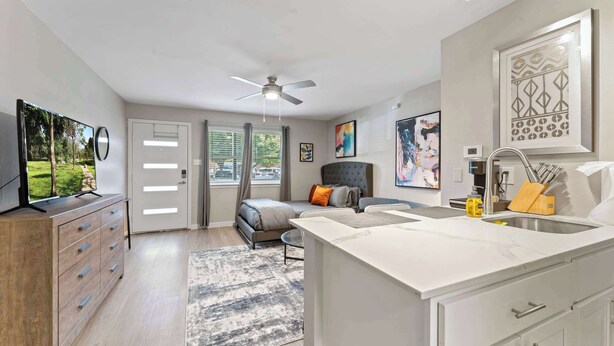 A modern hotel room with a bed, a desk, a kitchenette, and a TV on a dresser. - Efficiency studio close to Downtown and Domain (Austin)