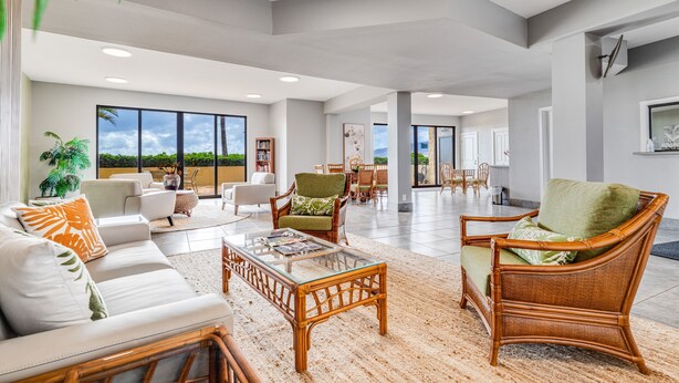A spacious living area with a large window, wicker furniture, and a view of the outdoors. - Kihei Beach, #307 1 Bedroom Condo by RedAwning (Kihei)