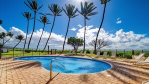 A swimming pool with a brick deck, surrounded by palm trees and a fence. - Kihei Beach, #307 1 Bedroom Condo by RedAwning (Kihei)