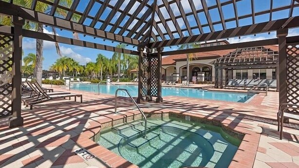 Un área de piscina con hidromasaje, sillas de descanso y una pérgola.