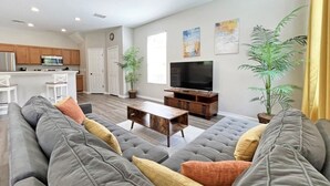 Una sala de estar moderna con un sofá gris, una mesa de centro de madera y un televisor de pantalla plana.