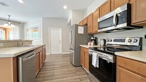 Una cocina moderna con armarios de madera, electrodomésticos de acero inoxidable y una isla central.
