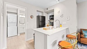Una cocina moderna con armarios blancos, una isla central y taburetes de bar.