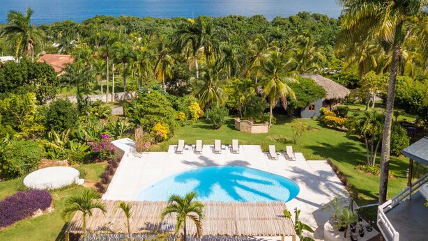 A tropical resort with a swimming pool, palm trees, and a view of the ocean. - Catalina Tropical Lodge (Cabrera)