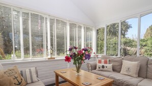 Una sala de estar acogedora con un sofá, una mesa de centro de madera y una ventana con persianas.