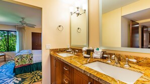 Une salle de bain d’hôtel avec deux lavabos, un grand miroir et un ventilateur de plafond.