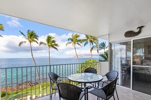 A balcony with a glass door, a round table, and four chairs. - Royal Mauian, #416 2 Bedroom Condo by RedAwning (Kihei)