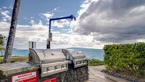 A barbecue grill with instructions, set against a scenic view of the ocean and clouds. - Kamaole Nalu, #105 2 Bedroom Condo by RedAwning (Kihei)