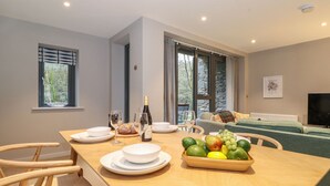 Zona menjador moderna amb taula de fusta preparada per a dinar, una ampolla de vi i un plat de fruita.
