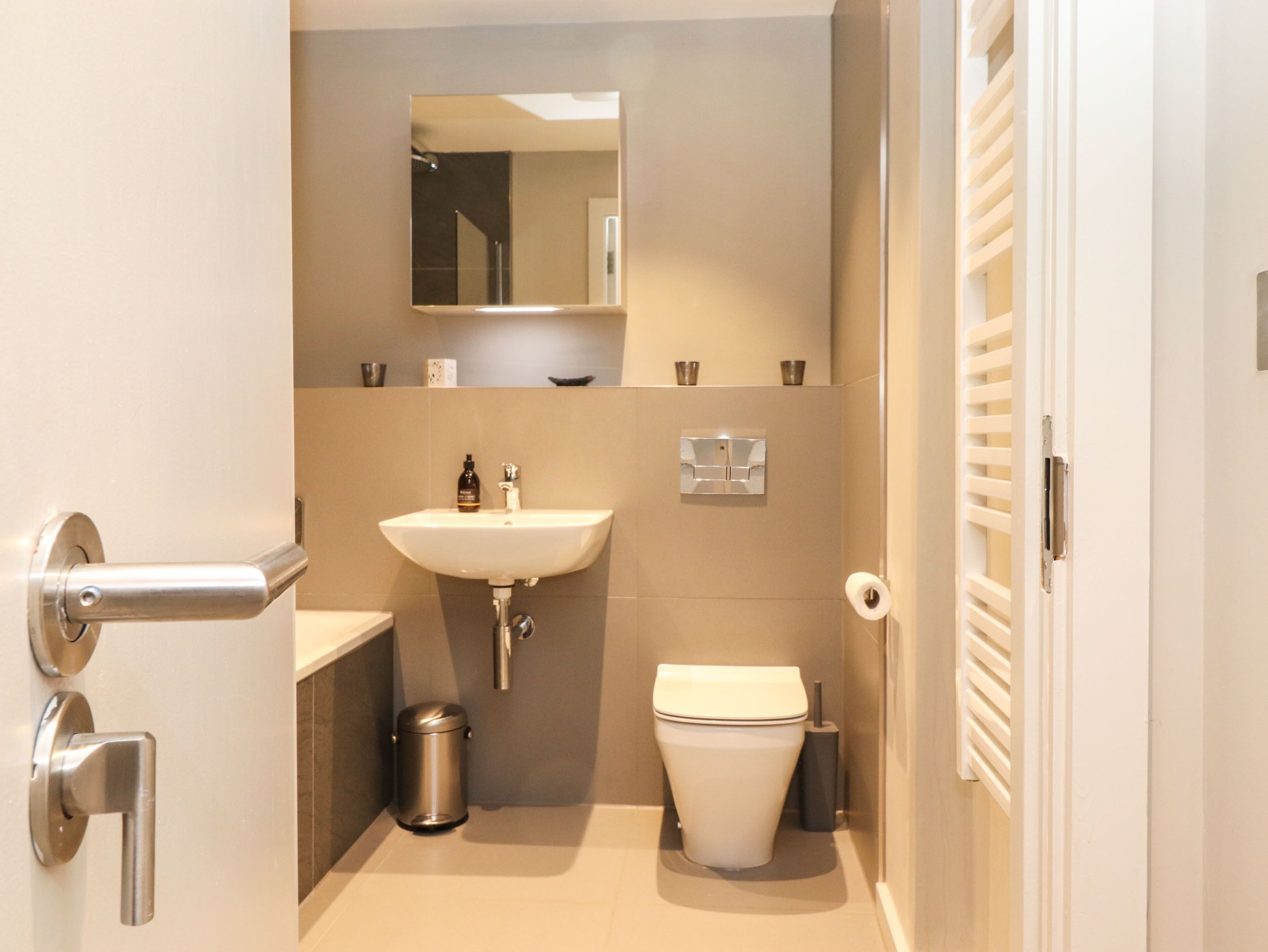 A bathroom with a sink, toilet, and a mirror.
