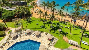 Un complexe hôtelier doté d’une piscine, d’une plage et de palmiers.