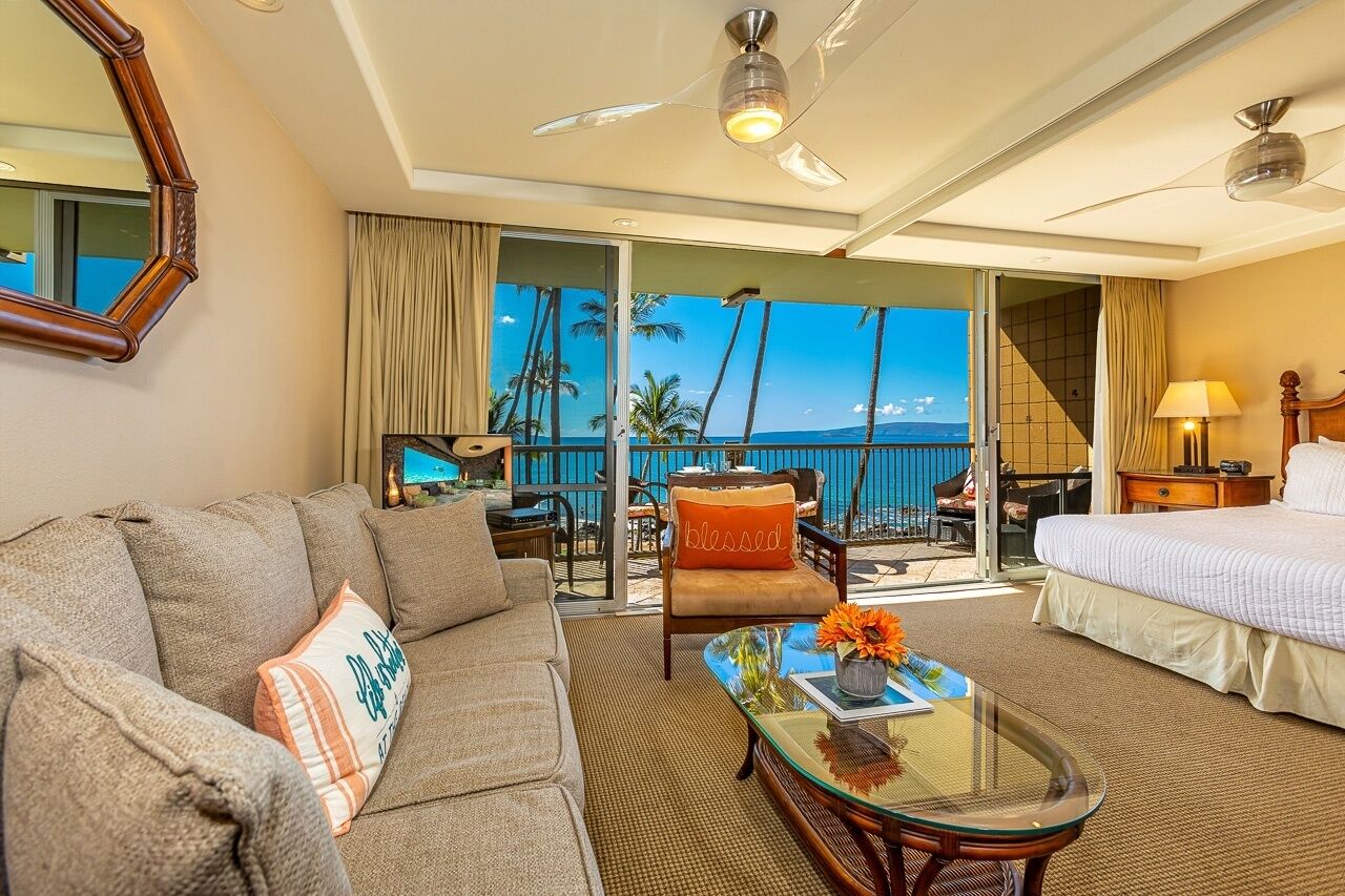 A hotel room with a balcony, a sofa, a bed, and a glass coffee table.