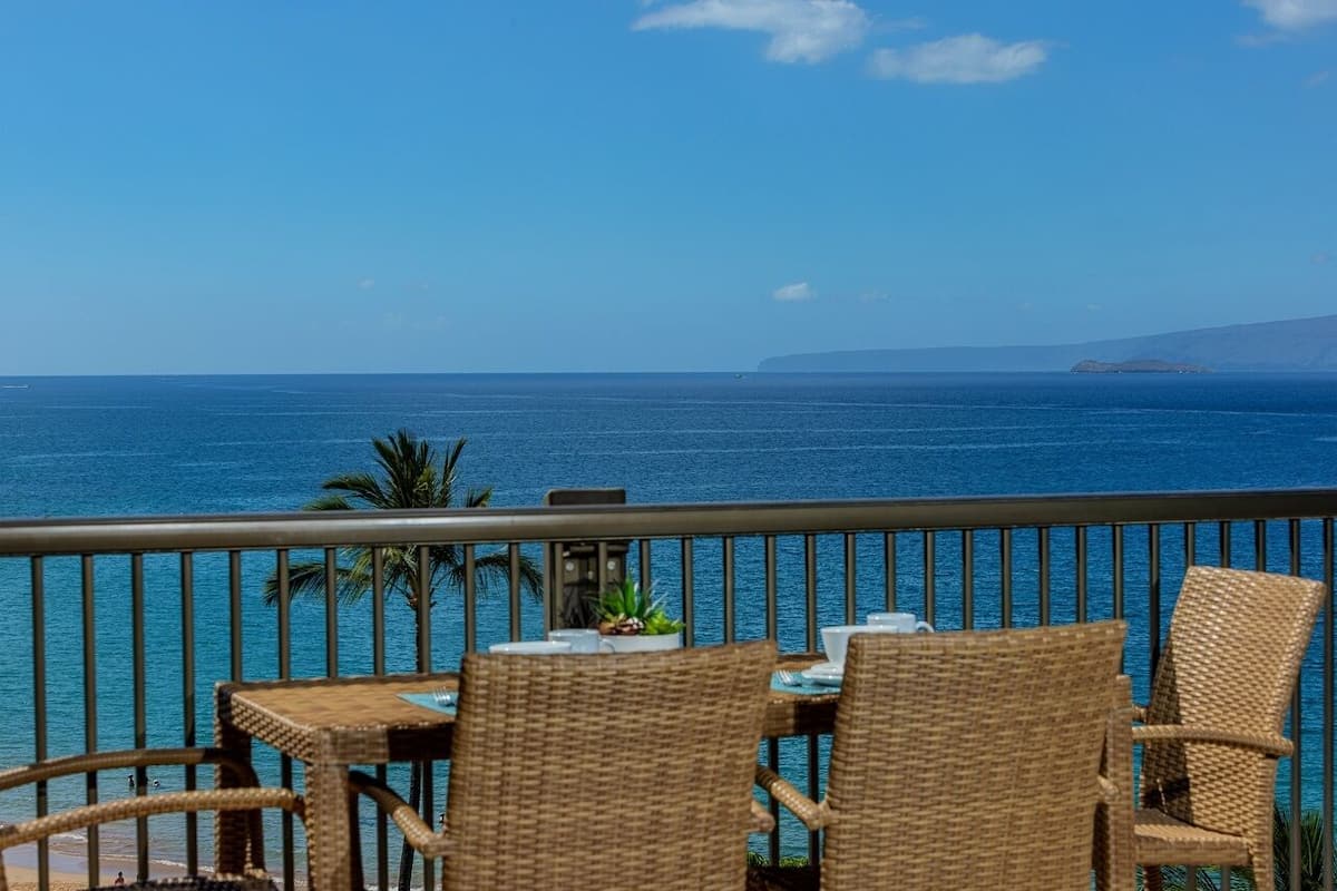 A balcony with wicker furniture and a view of the ocean.