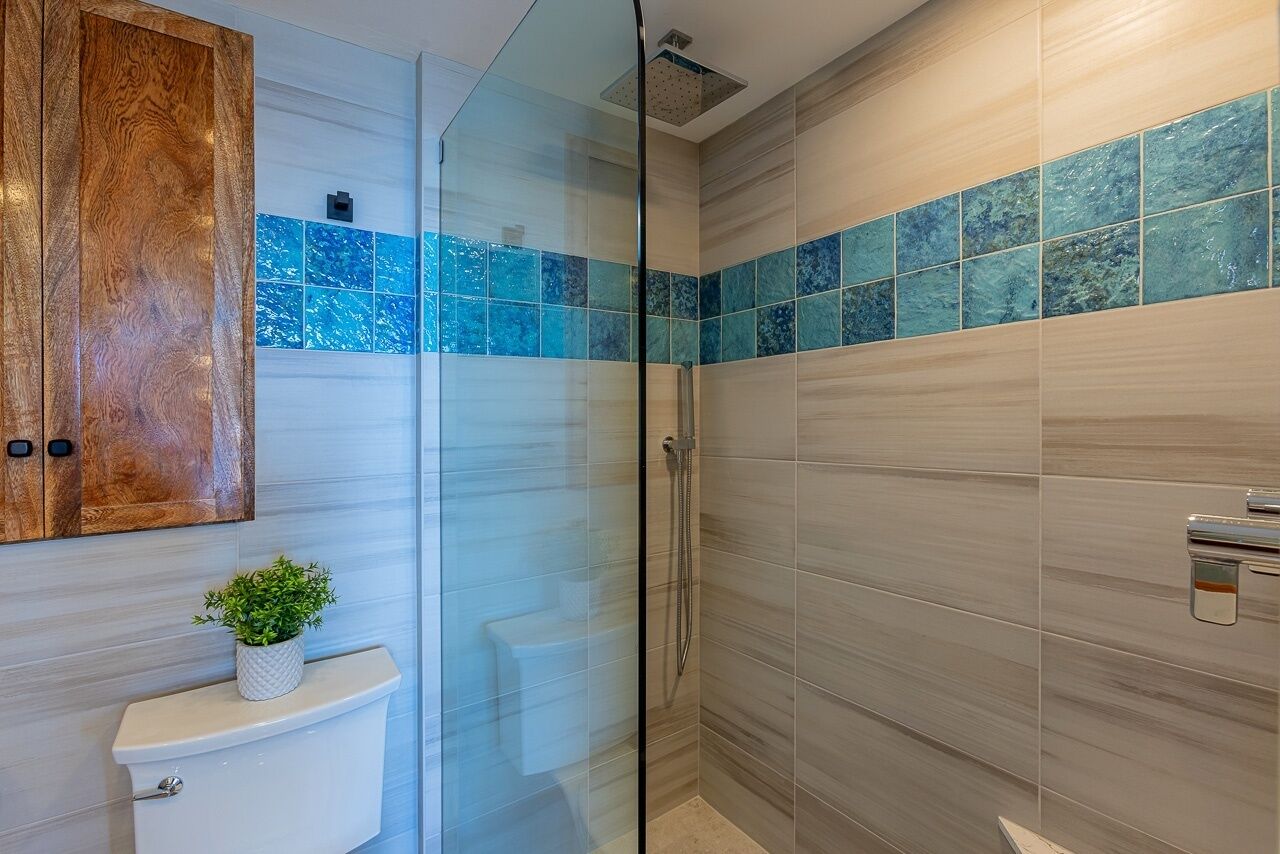 A modern bathroom with a glass shower enclosure, a wooden cabinet, and a white toilet.