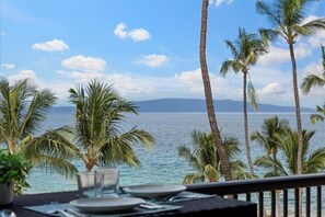A table set for dining with a view of the ocean and palm trees. - Mana Kai by Coldwell Banker Island Vacations (Kihei)