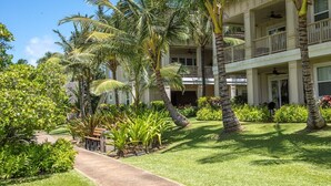Ein mehrstöckiges Hotel mit üppigem Garten, Palmen und einem Weg zum Eingang.