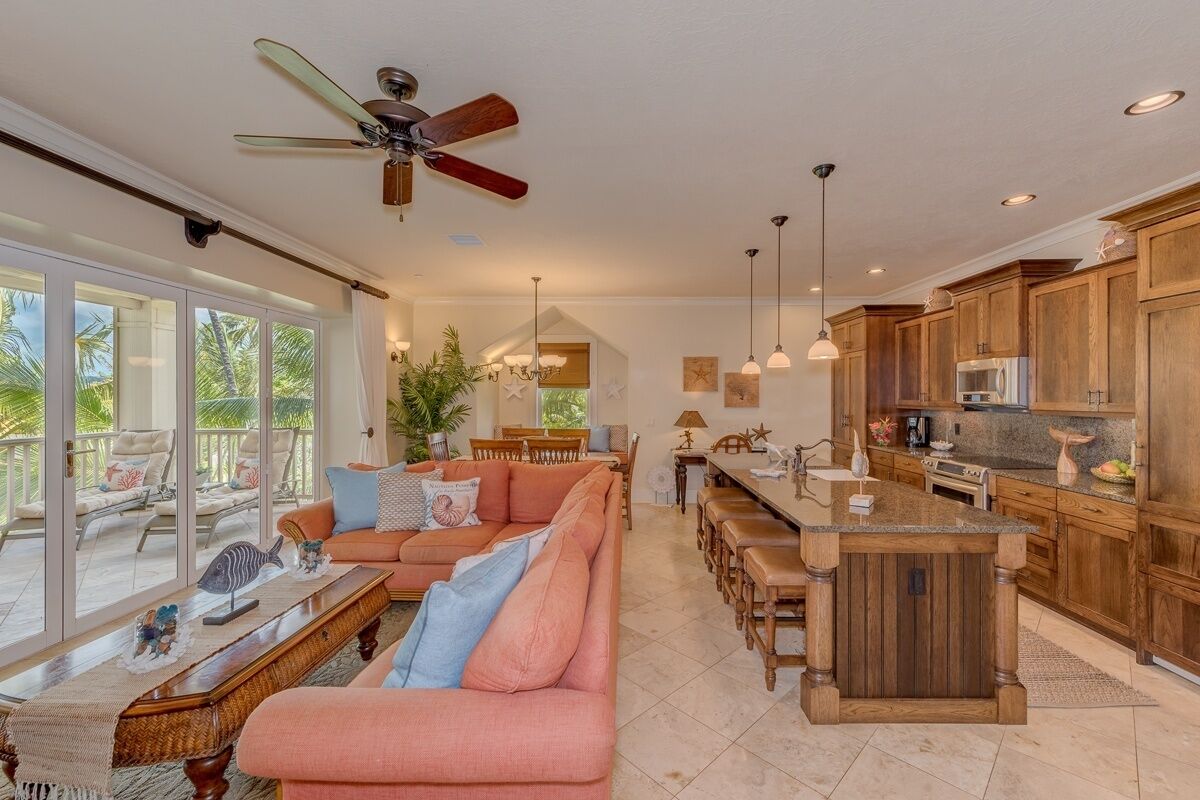 A spacious living area with a large sofa, a dining table, and a kitchen area with wooden cabinets and a central island.