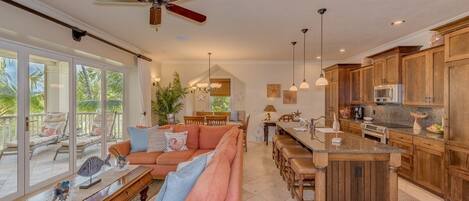 A spacious living area with a large sofa, a dining table, and a kitchen area with wooden cabinets and a central island.