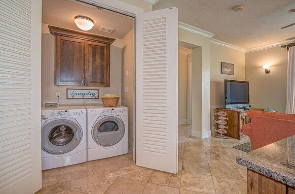 A laundry room with two front-loading washers, a wooden cabinet above, and a sign that says "Laundry".