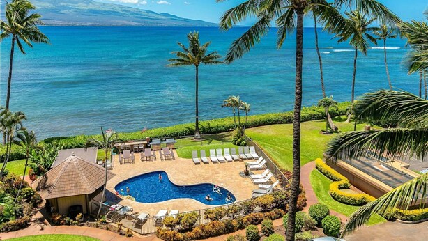 Un resort con piscina, sillones de descanso y vistas al océano.