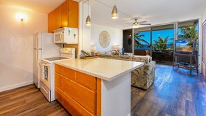 Una cocina moderna con armarios de madera, una isla central y vistas al océano a través de amplios ventanales correderas.