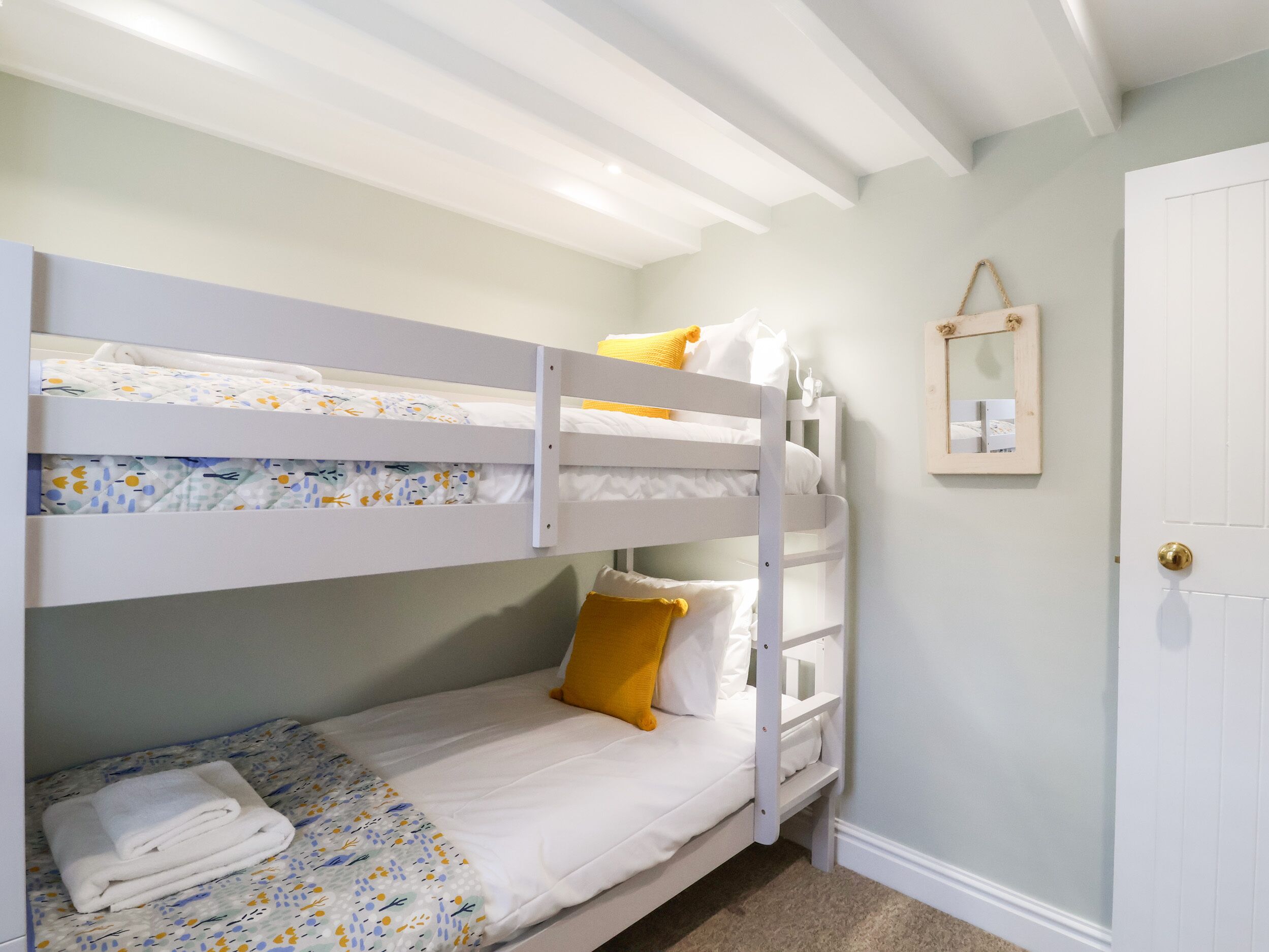 A bunk bed room with a door and a small mirror on the wall.