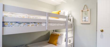 A bunk bed room with a door and a small mirror on the wall.