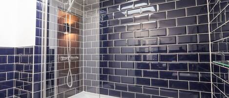 A modern bathroom with a glass-enclosed shower, a white bathtub, and a sink.