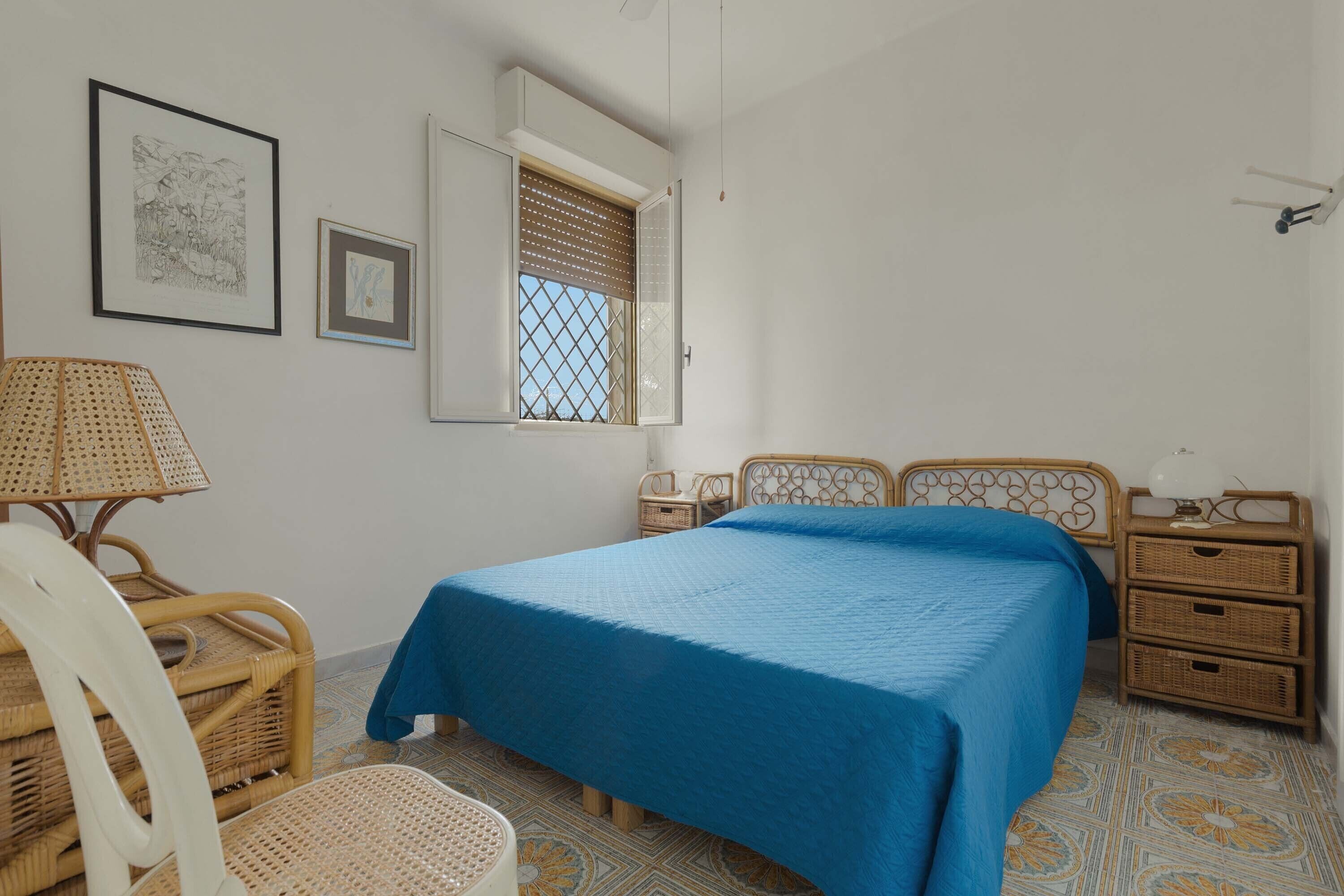Ein Schlafzimmer mit Bett, Sessel, Nachttisch und einem Fenster mit Blick.