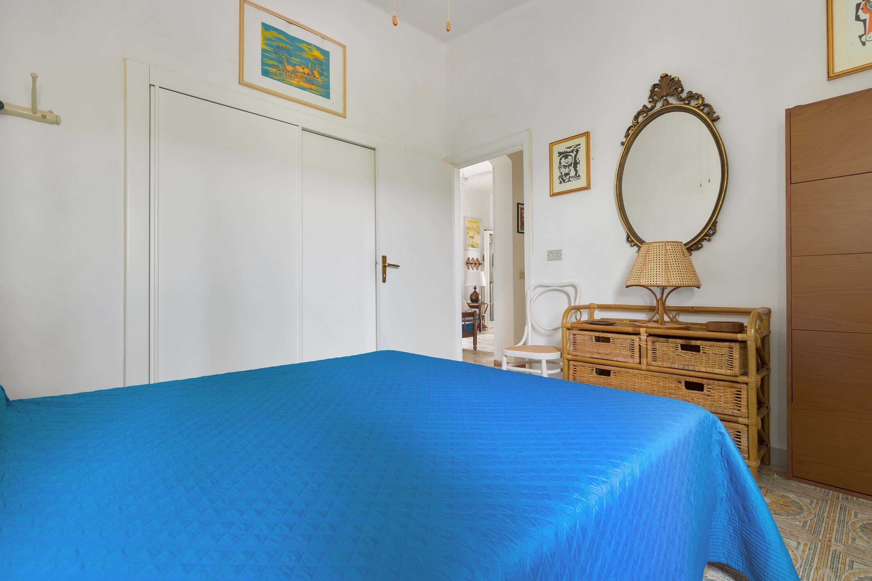 Un dormitorio con cama, cómoda, espejo y puerta.