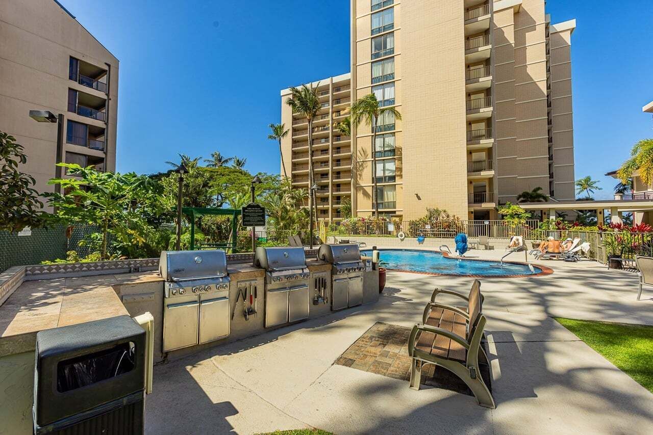 A poolside area with a barbecue setup and lounge chairs.