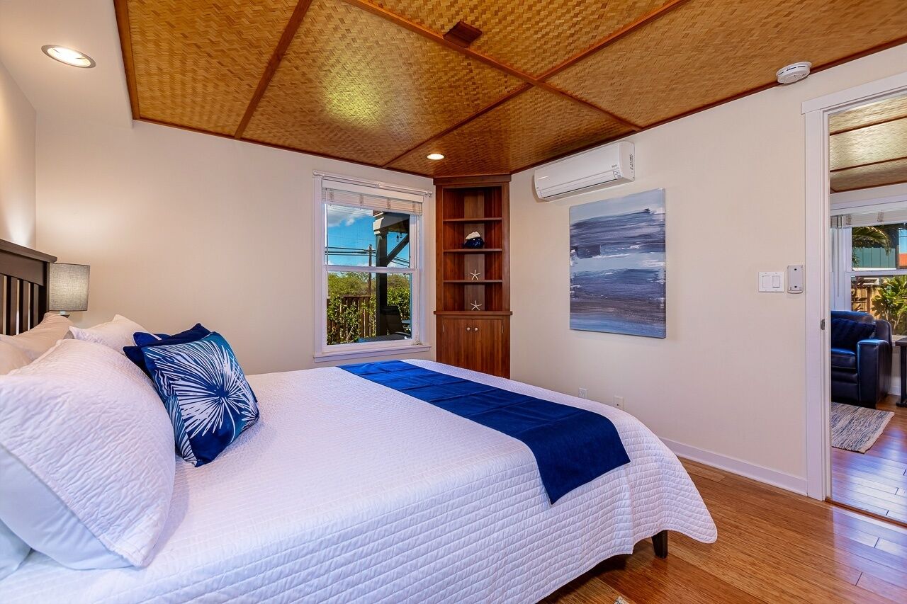 Ein Schlafzimmer mit einem großen Bett, Holzbalkendecke und Blick ins Freie.