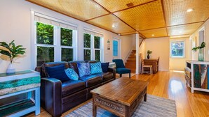 A spacious living room with a leather sofa, wooden coffee table, and a staircase leading to another level. - The Cove Hale 4 Bedroom Home (Kihei)