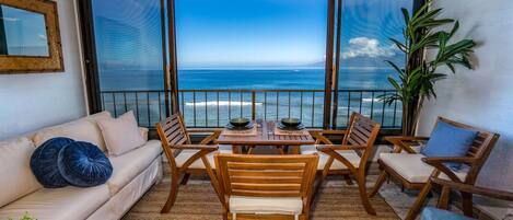 Un balcon avec vue sur l’océan, aménagé avec une table et des chaises, un canapé et un pot de fleurs.