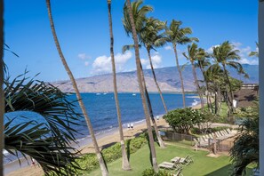 A coastal view with palm trees, a beach, and a mountainous backdrop. - Kihei Beach, #306 1 Bedroom Condo by RedAwning (Kihei)