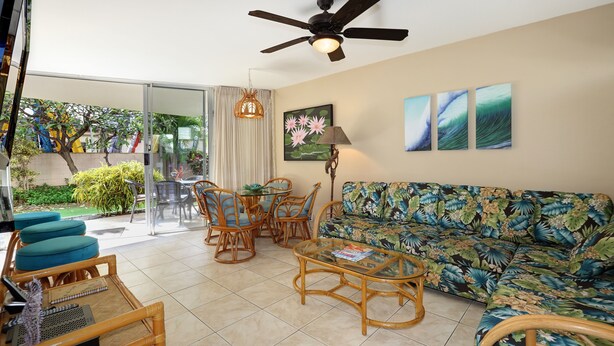 A living room with a ceiling fan, a sofa, a coffee table, and a dining area with chairs and a table. - Kamaole Nalu, #102 2 Bedroom Condo by RedAwning (Kihei)