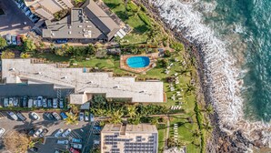 An aerial view of a coastal property with a swimming pool, parking area, and a beach. - Kamaole Nalu, #102 2 Bedroom Condo by RedAwning (Kihei)
