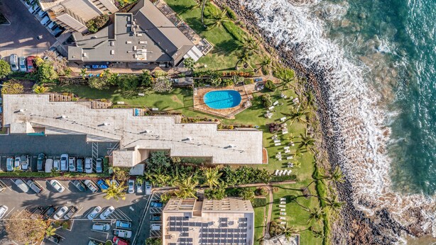 An aerial view of a coastal hotel with a swimming pool, parking area, and ocean view. - Kamaole Nalu, #102 2 Bedroom Condo by RedAwning (Kihei)