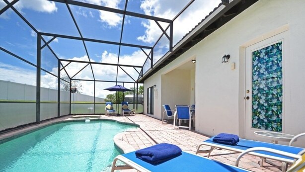 An indoor swimming pool with clear blue water, surrounded by lounge chairs and umbrellas. - Happy Daze 4 Bedroom Home by RedAwning (Clermont)