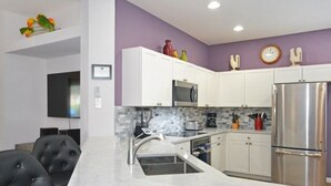 A modern kitchen with white cabinets, a stainless steel refrigerator, and a marble countertop. - Happy Daze 4 Bedroom Home by RedAwning (Clermont)