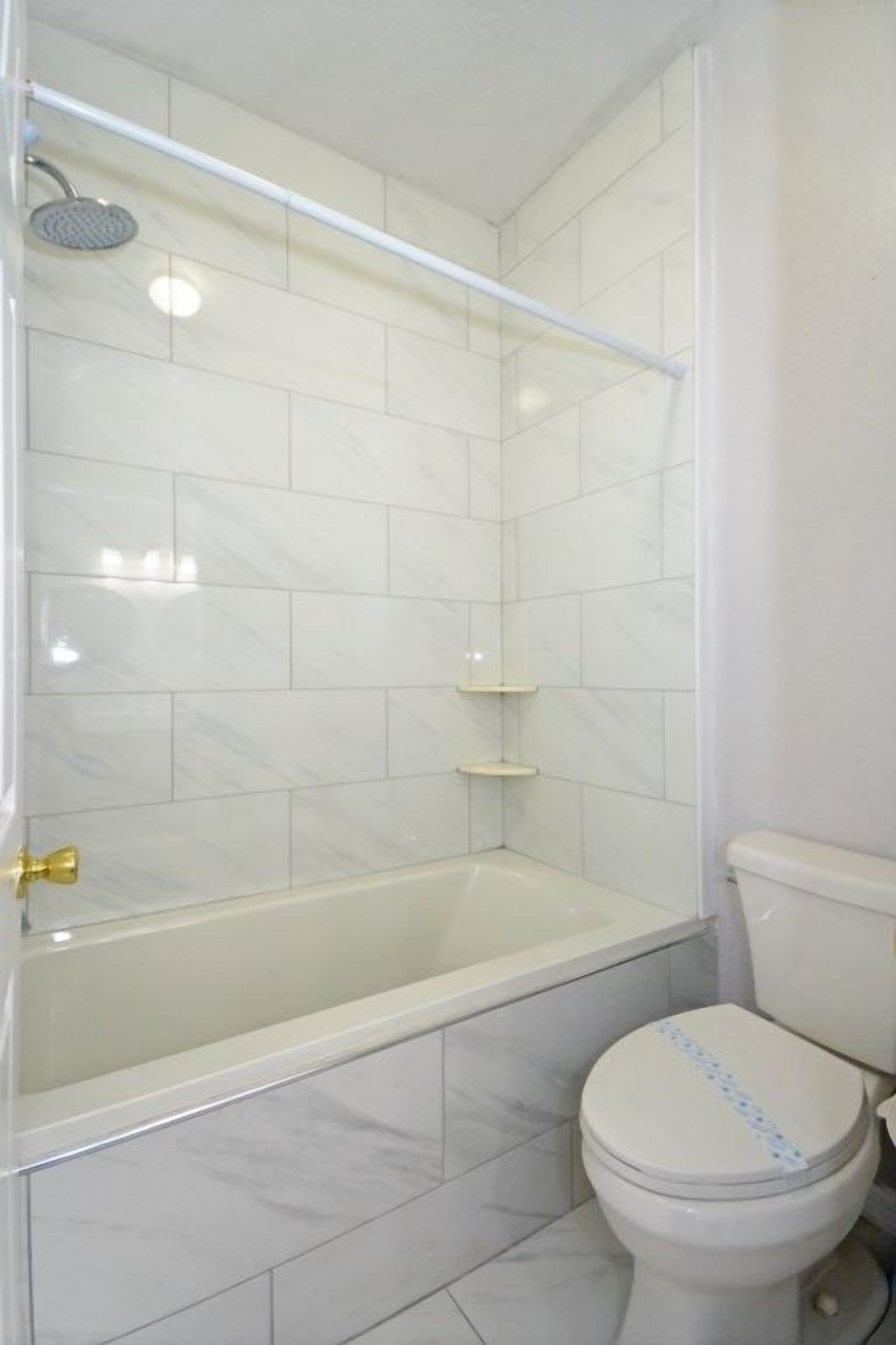 A bathroom with a bathtub, toilet, and a shower area.
