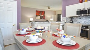 A dining area with a central island, white cabinets, and a kitchen in the background. - Happy Daze 4 Bedroom Home by RedAwning (Clermont)
